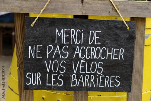 Merci de ne pas accrocher vos vélos sur les barrières. Inscription blanche sur grande ardoise noire.