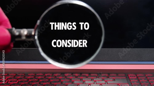 A gloved hand holds a magnifying glass over a luminous keyboard. The lens reveals and emphasizes the words Things To Consider for enhanced examination
