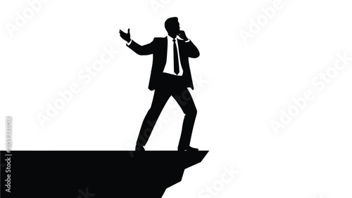 Silhouette of a determined businessman standing precariously on the edge of a cliff while talking urgently on a mobile phone representing extreme pressure or critical decision making