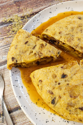Spanish tortilla slices on white plate with sauce