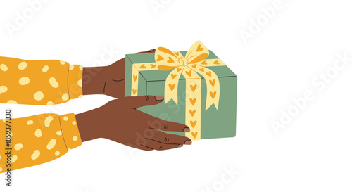 Two hands giving a green gift box with a yellow heart patterned ribbon as a gesture of kindness or birthday celebration.