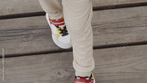 Top view of sneakers stepping on wooden pier. Symbolizes independence, everyday growth and first steps of maturity. High quality 4k footage