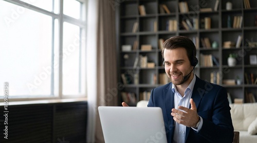 Smiling businessman in blue suit jacket engaged in online meeting with headset