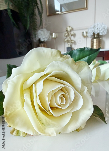 Handmade tea rose sculpted from air-dry clay lying on a table, with separate petals and green leaves nearby. Clay flower during crafting process. DIY art, handmade decoration, creative workshop
