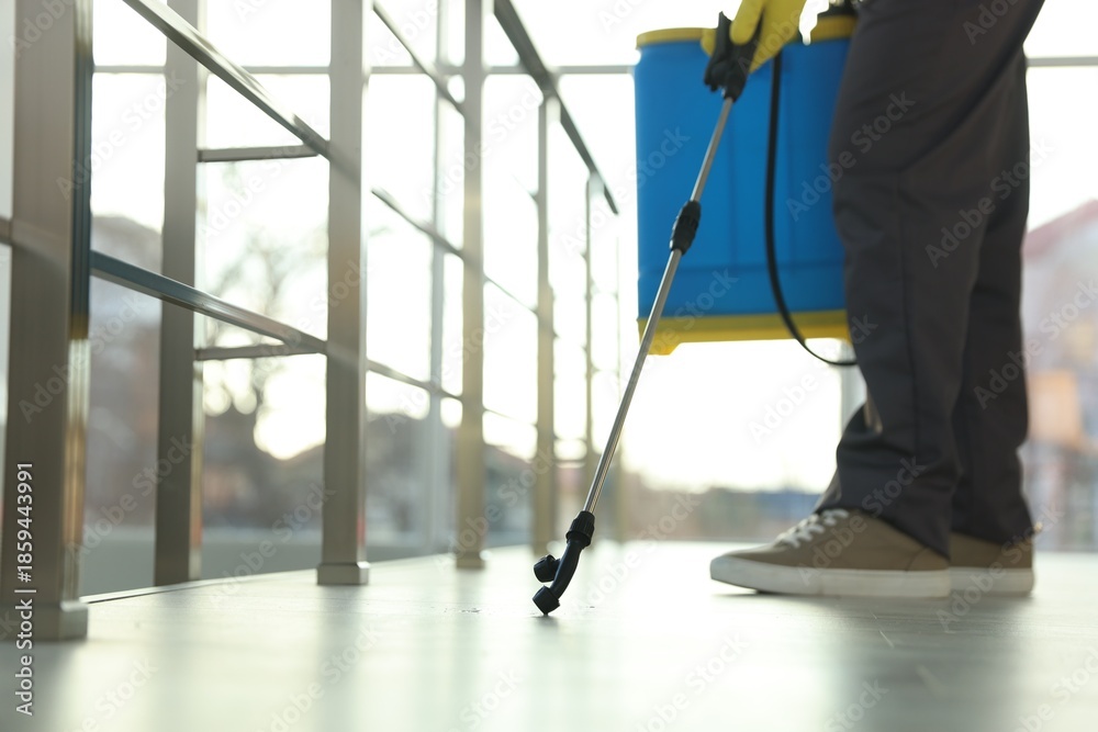 Fototapeta premium Pest control worker spraying insecticide indoors, closeup. Space for text