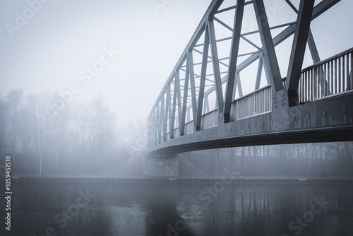 Metal bridge on the Mittellandkanal in Bramsche, Germany, in winter fog — moody canal landscape