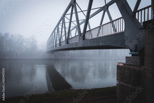 Metal bridge on the Mittellandkanal in Bramsche, Germany, in winter fog — moody canal landscape