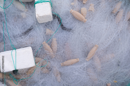 Close-up photograph of a traditional fishing net with foam floats. Professional photography with normal lens detail, natural lighting, coastal maritime atmosphere.