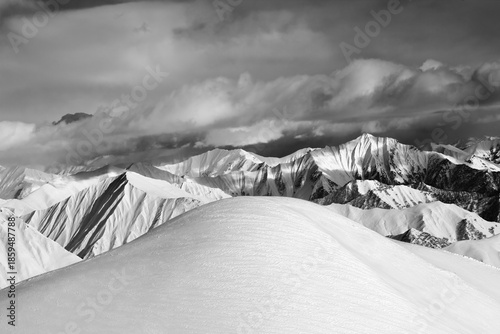 Black and white  off-piste snowy slope and cloudy mountains