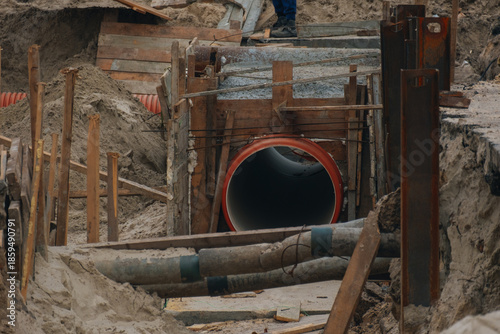 Repair of city utility networks and pipeline replacement. This photograph demonstrates the complex process of excavation, installation of protective structures, and the use of modern building material