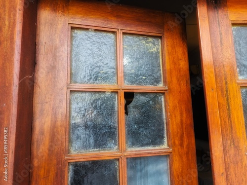 Old wooden window with cracked glass, rustic architecture detail showing age, decay, and vintage character