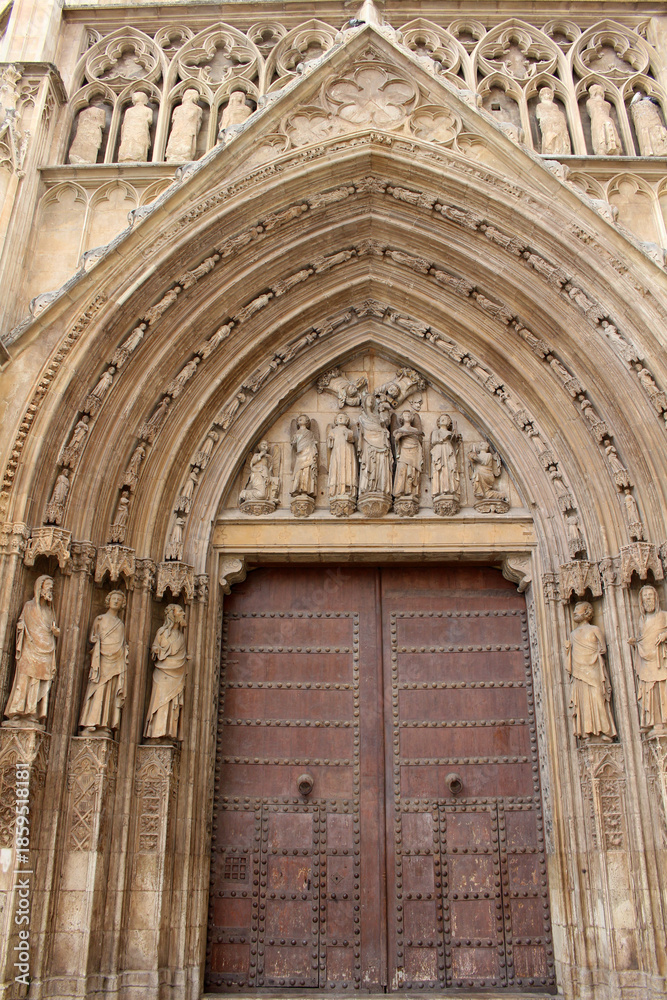 Obraz premium Entrance gate of Valencia Cathedral featuring historic Gothic stone architecture and religious details, taken in July 2024.