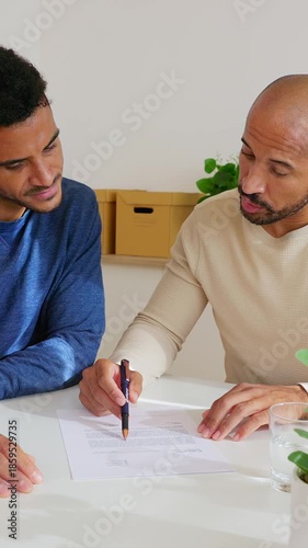 Vertical HD video of businessmen reviewing a contract and shaking hands after signing in a modern office. Professional colleagues completing a formal agreement. Recruitment and business concept.