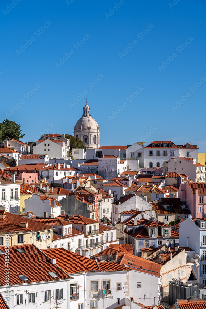 Obraz premium A telephoto view of the iconic white dome of the National Pantheon (Church of Santa Engracia) rising above the dense, colorful architecture and orange terracotta roofs of the Alfama neighborhood.
