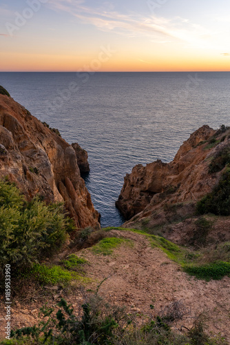 Golden sunset over the rugged limestone cliffs of Algarve coast in Lagos, Portugal. he warm evening light hits the rocky sea stacks and steep cliffs of Ponta da Piedade.