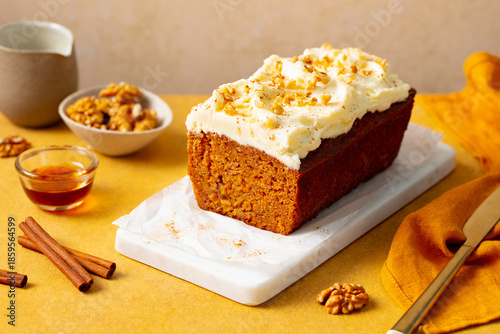 Carrot cake loaf on a white marble serving board. Yellow background. Close up.