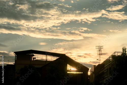 Silhouette of a building and radio tower against a golden sunset sky in Bangkok, Thailand
