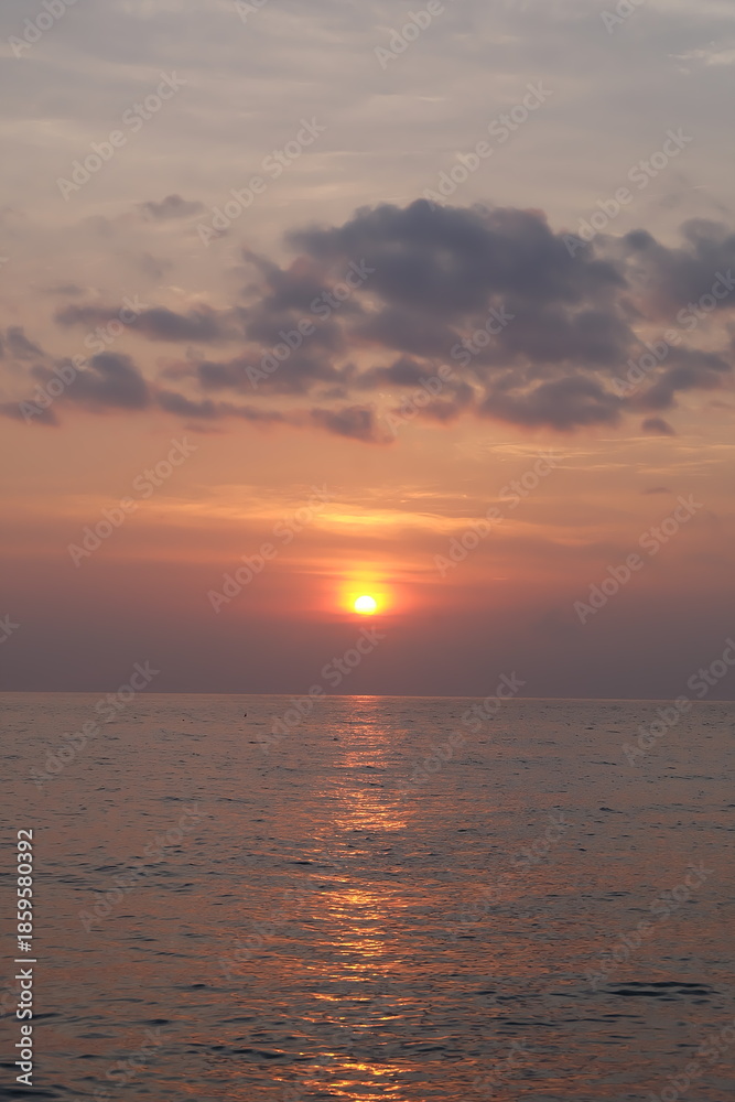 Fototapeta premium Golden Sunset Over Water with Dramatic Clouds and Reflections.