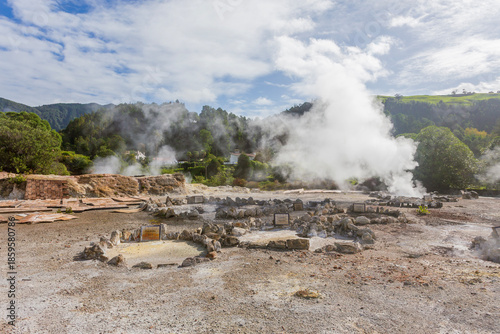 Wide landscape of Caldeiras das Furnas geothermal field with steam vents and boiling mud in São Miguel, Azores.