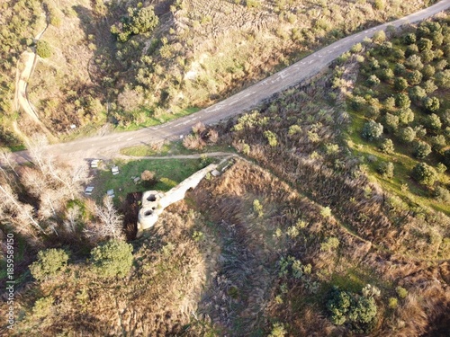 Scenic view of a road intersecting green fields and rocky terrain near a natural landmark