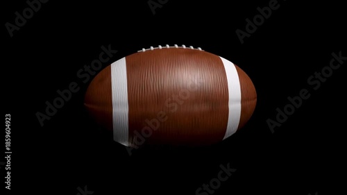 An isolated brown football sits on a black stage, its stitched panels and texture clearly visible!!!