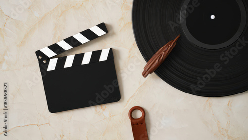 Artistic Still Life Composition Featuring a Clapperboard, Vinyl Record, Wooden Object, and Leather Accessory on a Marble Background for Creative Projects