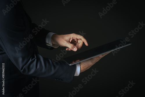 Side view of professional businessman holding and interacting with a black digital tablet