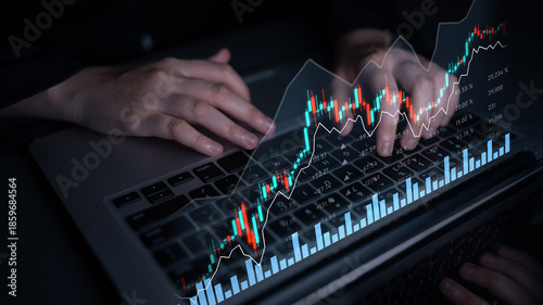 A trader hands on a laptop keyboard with dynamic graphs and charts projecting market trends and stock performance in a modern trading setting. Scalp
