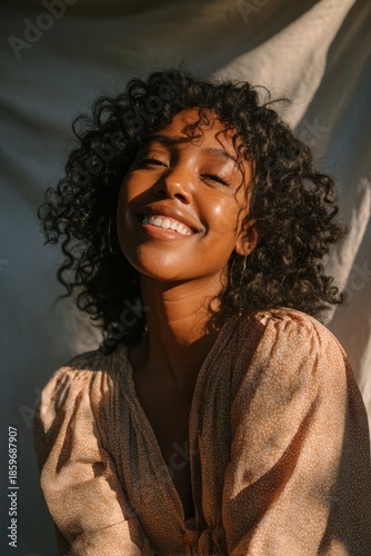 Portrait of a confident young woman with curly hair smiling warmly in soft daylight, wearing a light patterned dress, conveying joy, authenticity, and positive lifestyle mood