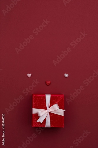 Gift Box on Brown Background With Floating Heart Shapes Around It