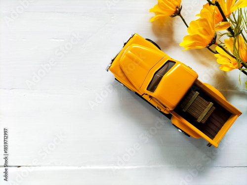 Yellow toy truck on a white wood surface. 