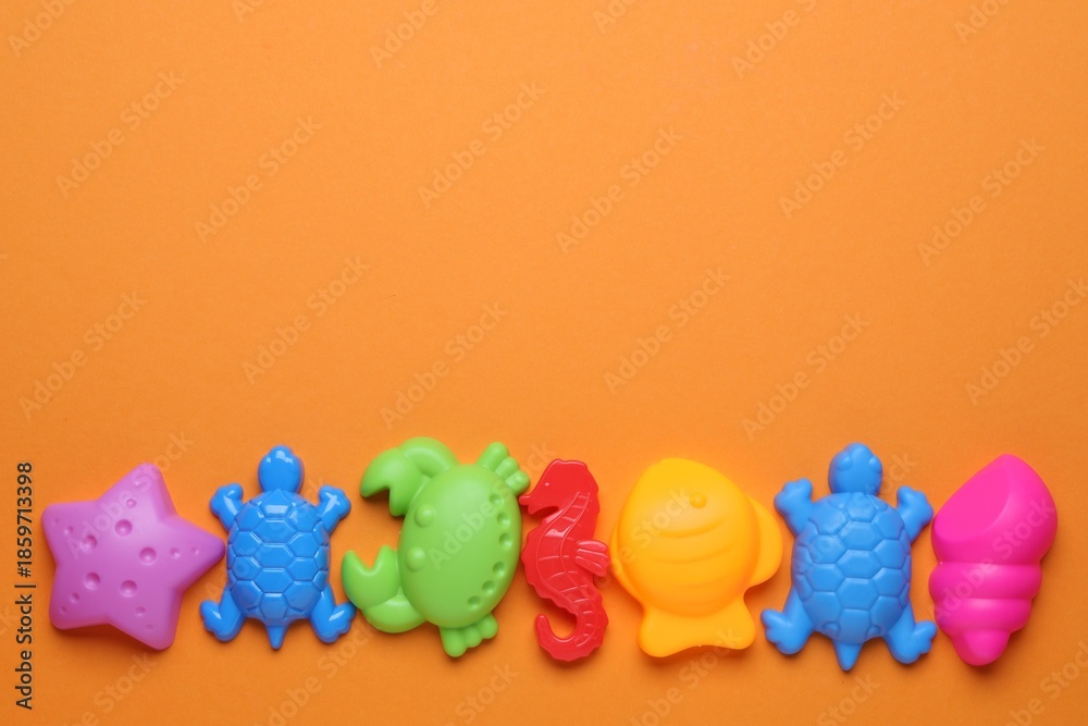 Fototapeta premium Children's beach toys on orange background, flat lay. Space for text