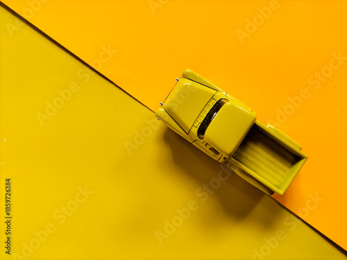 Yellow toy truck placed on a two-toned yellow background. 
