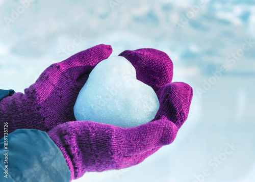 Hands in knitted mittens with heart of snow in winter day, selective focus. Love concept. Valentine day concept.