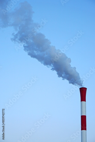 Fototapeta kuchenna Red and white tall chimney with smoke at blue sky