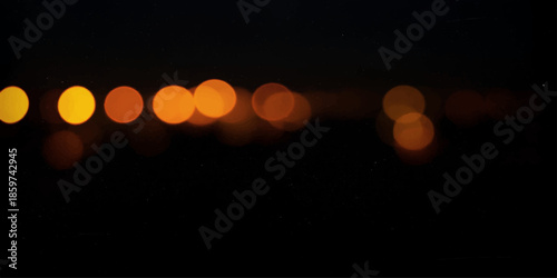 A glowing light bulb on a dark wall shines with colorful bokeh circles and blurred city street lights, creating a bright festive glow amidst the night traffic
