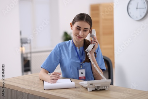 Medical assistant answering phone at reception in clinic
