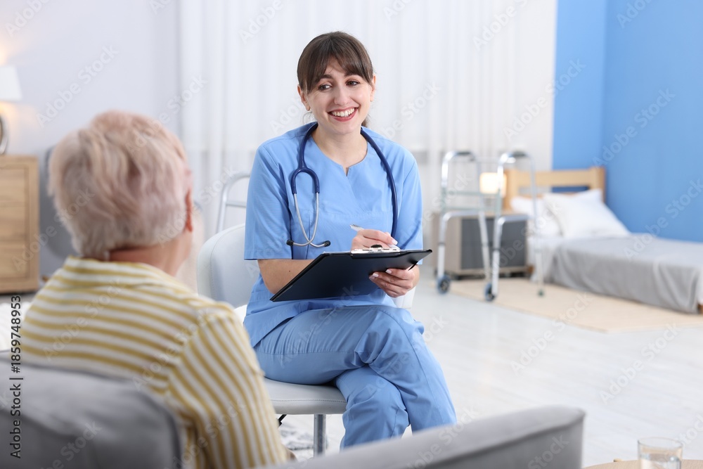 Fototapeta premium Care worker asking senior woman about her wellbeing at retirement home