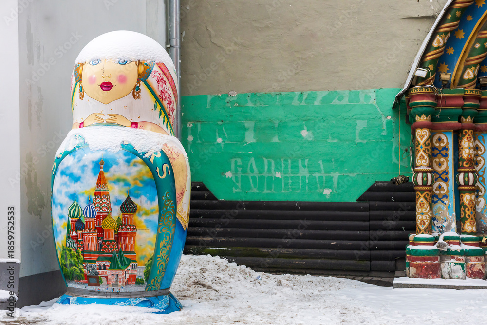 Fototapeta premium Moscow, Russia, 29 December 2025, A giant decorative Matryoshka nesting doll statue painted with St. Basil's Cathedral standing outdoors in the snow. A street decoration