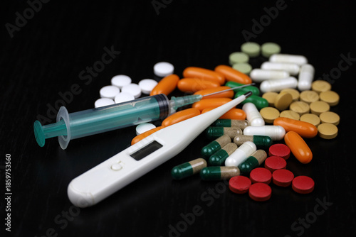 Digital thermometer, syringe and pills on table. Concept of fever, antipyretic, vitamins