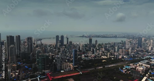 Cinematic aerial view of the Mumbai city skyline during the monsoon season, with dramatic clouds creating a moody and atmospheric backdrop.