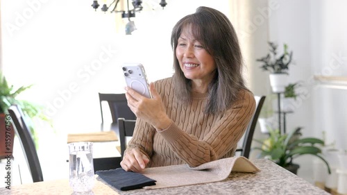 Happy smiling woman enjoying talking smartphone video chat relaxing sitting in bright light home 