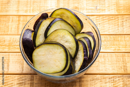 Fresh Sliced Eggplant in Glass Bowl on Wooden and Dark Background