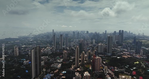 Cinematic aerial view of the Mumbai city skyline during the monsoon season, with dramatic clouds creating a moody and atmospheric backdrop.