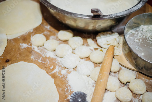 Close-up of an elderly woman's female hands rolling out dough with a wooden rolling pin. Making homemade pies and chebureks.