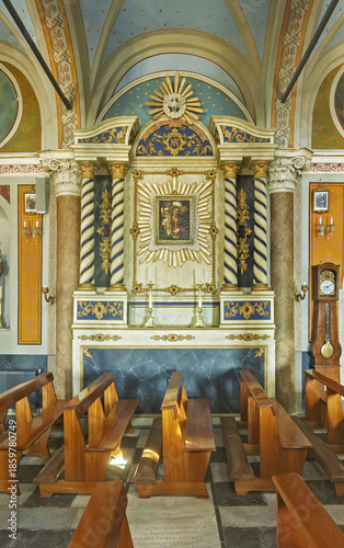  the Cathedral of Saint George in Ano Syros showcasing  columns, arches, and a vaulted ceiling with intricate artwork. The central altar is draped in white cloth and framed by golden columns 