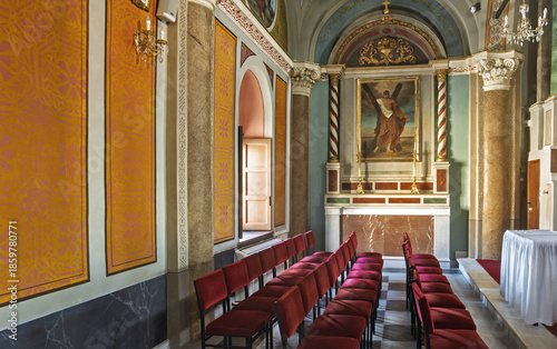  the Cathedral of Saint George in Ano Syros showcasing  columns, arches, and a vaulted ceiling with intricate artwork. The central altar is draped in white cloth and framed by golden columns 