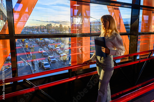 Woman enjoying city view from bright modern building during golden hour at bustling urban location