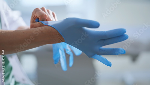 Bild auf Leinwand Doctor hands putting gloves preparing to medical procedures at cabinet closeup