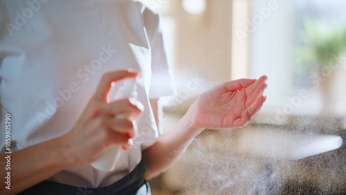 Obraz na płótnie Closeup waitress disinfecting hands applying antibacterial spray at restaurant